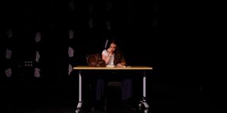 Healy's character in Completely Bloody Incoherent sat on a desk