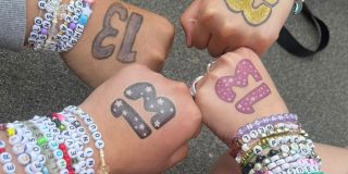 Taylor swift friendship bracelets on the arms of four friends with the number 13 painted on their hands.