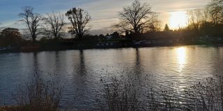 Sun setting over a river with trees on the far side